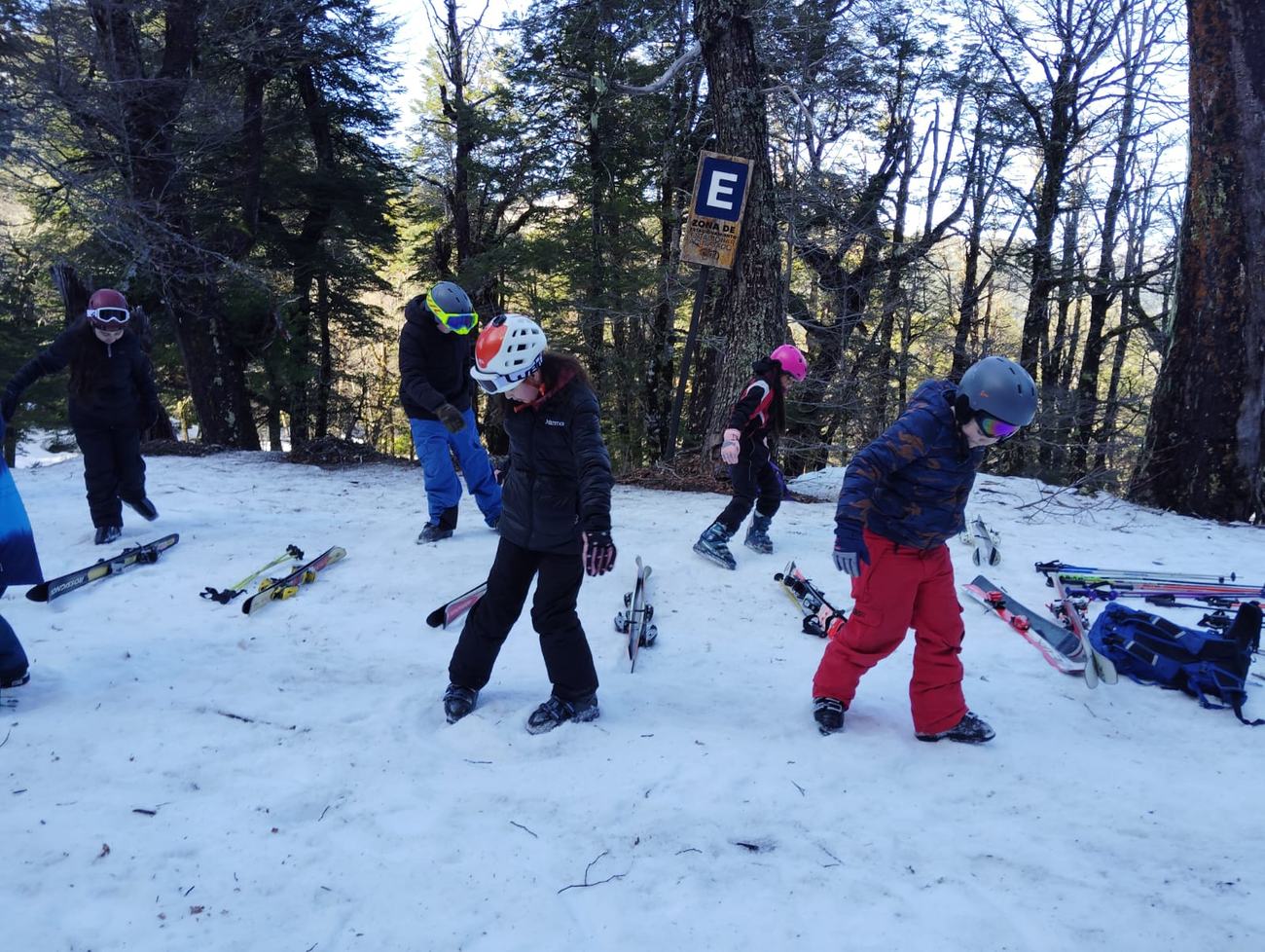 Niños y niñas haciendo ejercicios de equilibrio en la nieve, entre el bosque