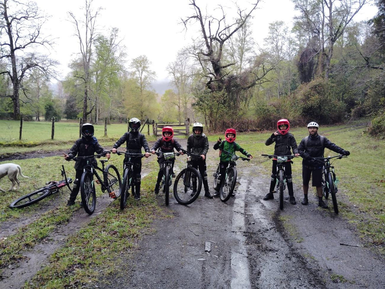 Grupo de niños con bicicletas de montaña y cascos junto a su monitor