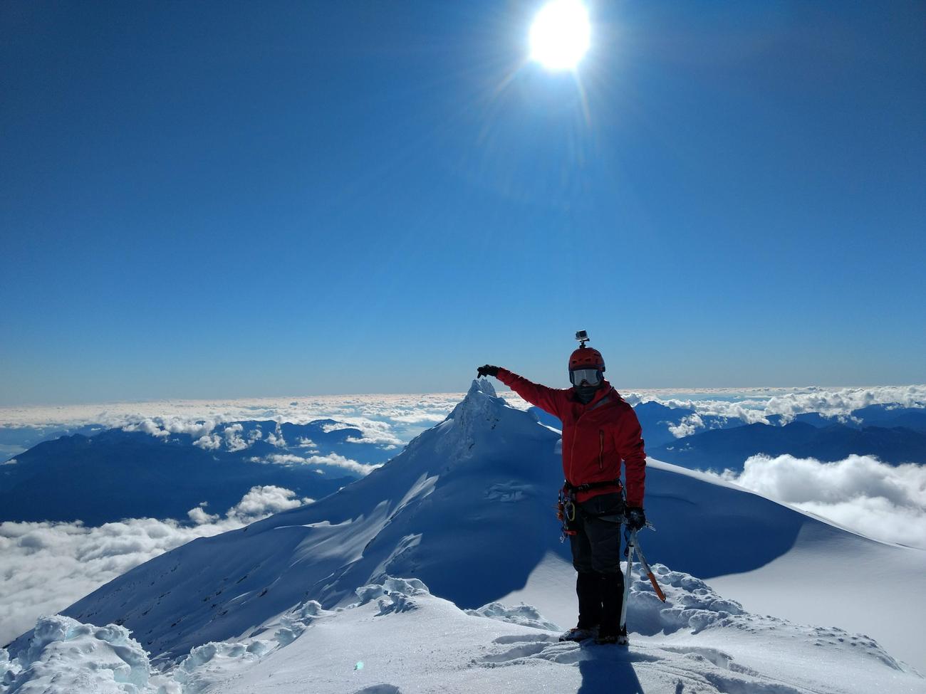 Montañista en la cumbre invernal señalando el pico Choshuenco