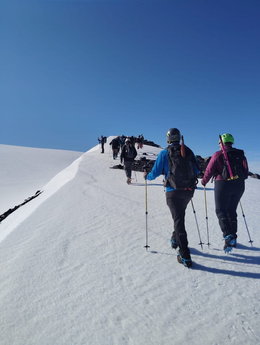 Grupo con crampones y piolet ascendiendo por un filo nevado