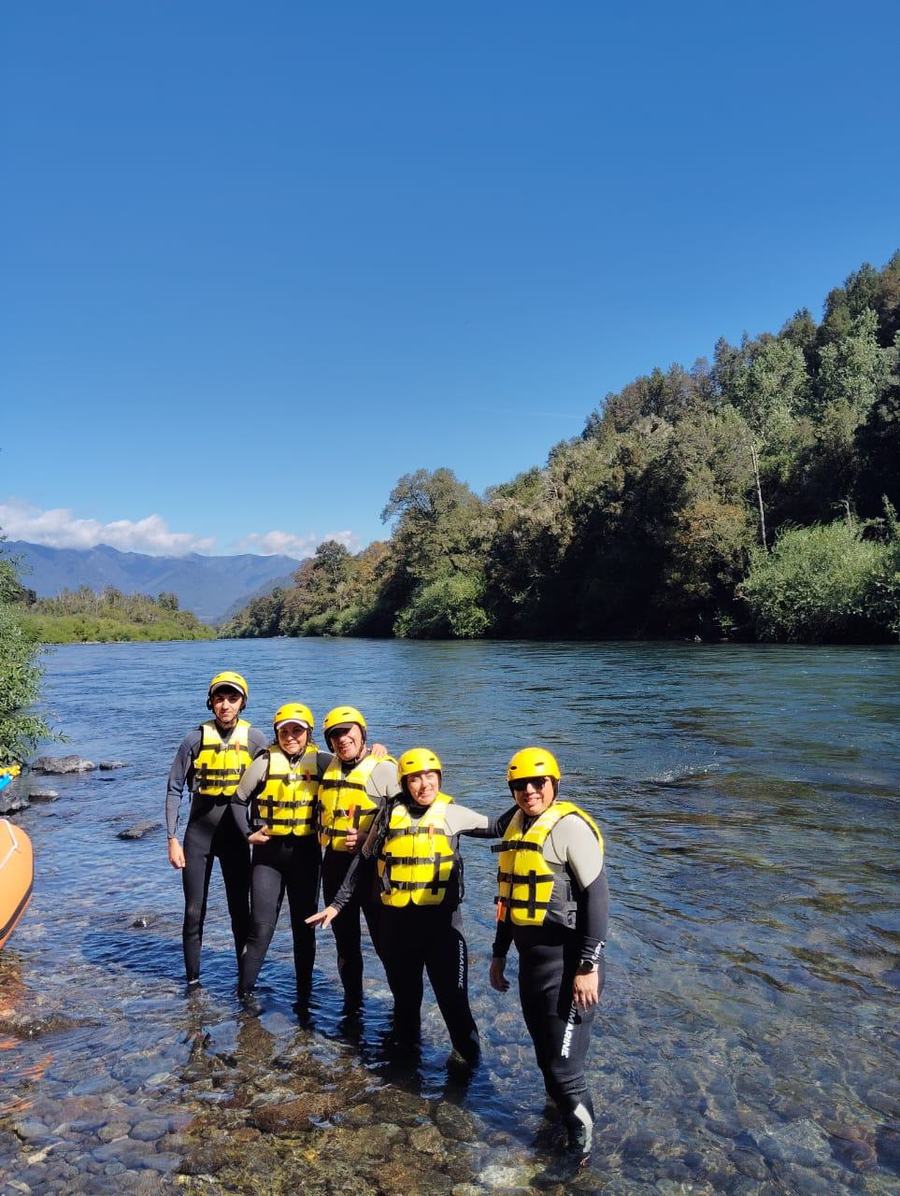 Grupo con cascos y chalecos en el río antes del rafting