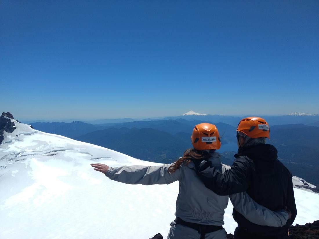 Participantes con cascos Wechuntu mirando los lagos y volcanes desde la cumbre